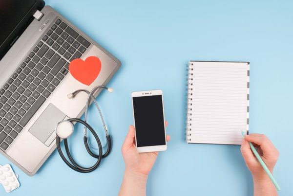 ordinateur, téléphone mobile, stéthoscope et calepin posés sur une table
